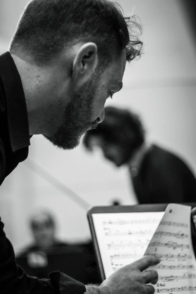 In bianco e nero, Paolo Censi si china a leggere una partitura sul leggio