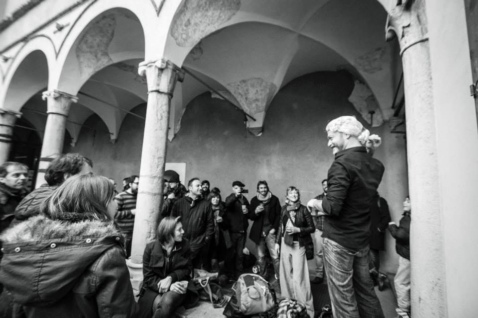 Spettacolo itinerante sotto un porticato: un attore con parrucca settecentesca parla al pubblico