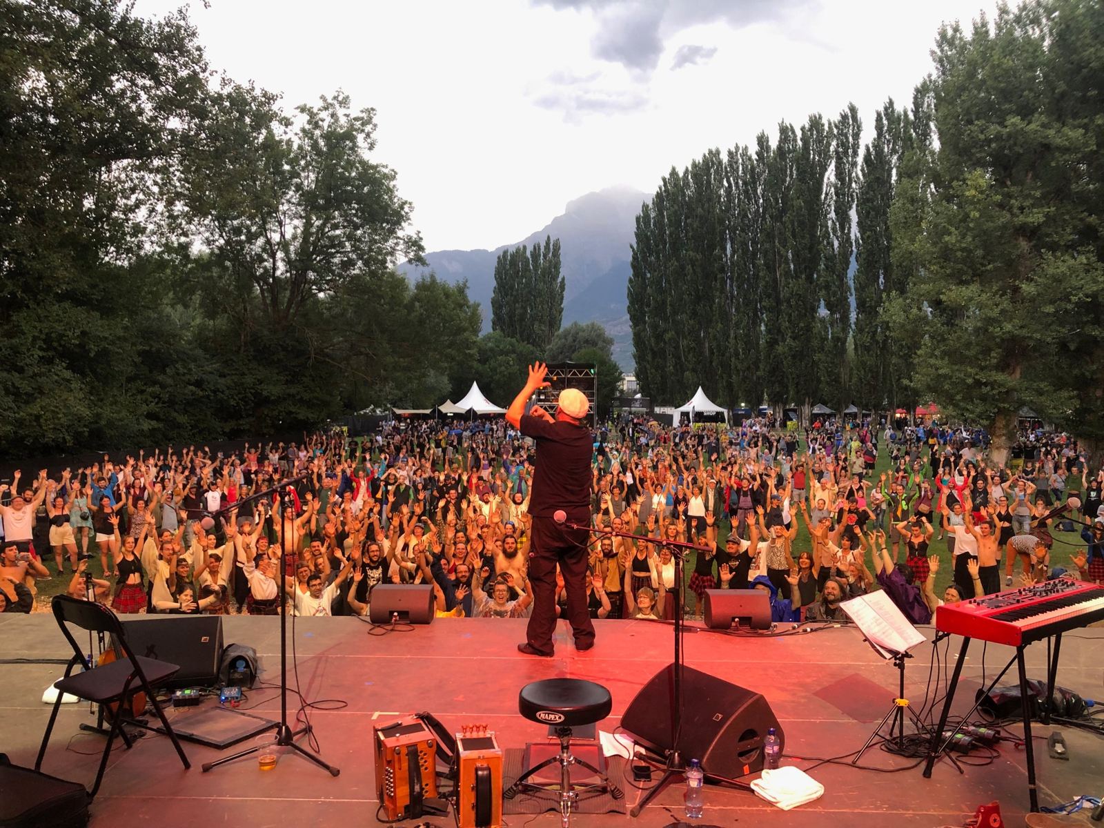Dal palco di un festival all'aperto, centinaia di persone ballano con le braccia alzate davanti ad Andrea Capezzuoli e Compagnia