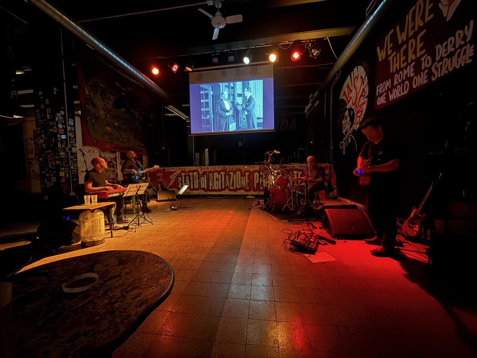 Concerto dal vivo davanti a un film muto proiettato su un grande schermo: Paolo alla tastiera Nord rossa, con basso, batteria e chitarra